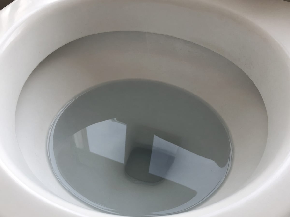 Superfície da água parada no interior de uma bacia sanitária, sem pessoas.